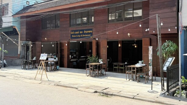 Un restaurante con terraza, un cartel y fachada de madera.