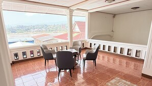 Un balcón con mesa y sillas, vista a edificios y baldosas de piso con diseño.