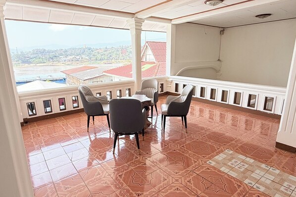 A balcony with a table and chairs, a view of buildings, and patterned floor tiles.
