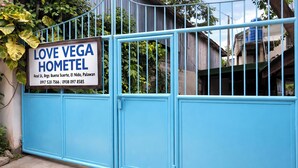 Sininen metalliportti, jossa on kyltti, jossa lukee ”LOVE VEGA HOMETEL” sekä osoite ja yhteystiedot.