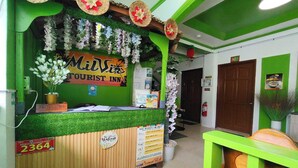Ein Empfangstisch mit einem Schild für 'Milvis Tourist Inn', einer Gewerbeanmeldung und einem Willkommensschild.