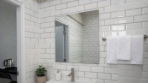 A bathroom with white subway tiles, a white sink, a mirror, and a towel rack. - The 9 Motel (Ngao)