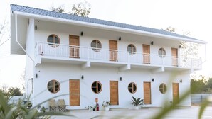 A two-story building with a flat roof, multiple balconies, and circular windows. - The 9 Motel (Ngao)