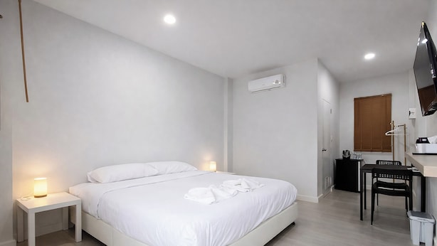 A modern hotel room with a large bed, bedside tables with lamps, a desk with a chair, and a flat-screen TV mounted on the wall. - The 9 Motel (Ngao)