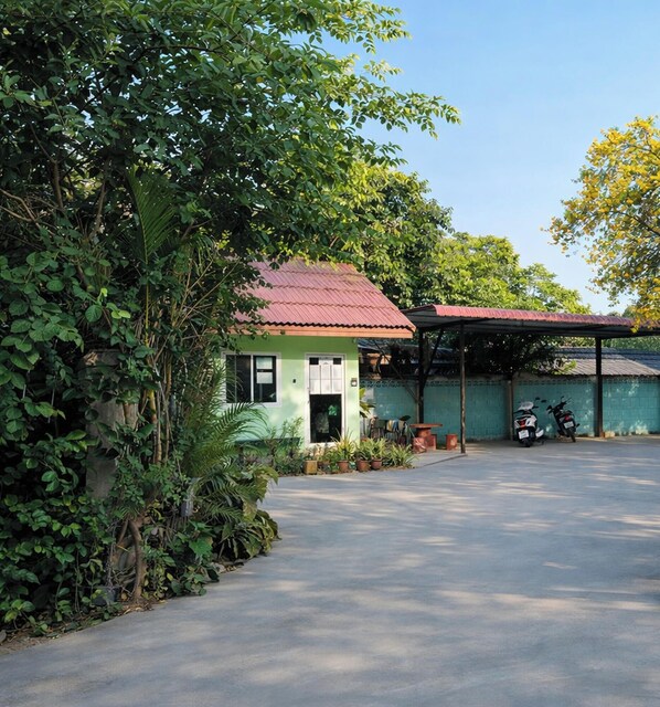 A small, single-story building with a green facade and a red roof, surrounded by lush greenery and a paved driveway. - F.H.R Krabi City Hotel (Krabi)