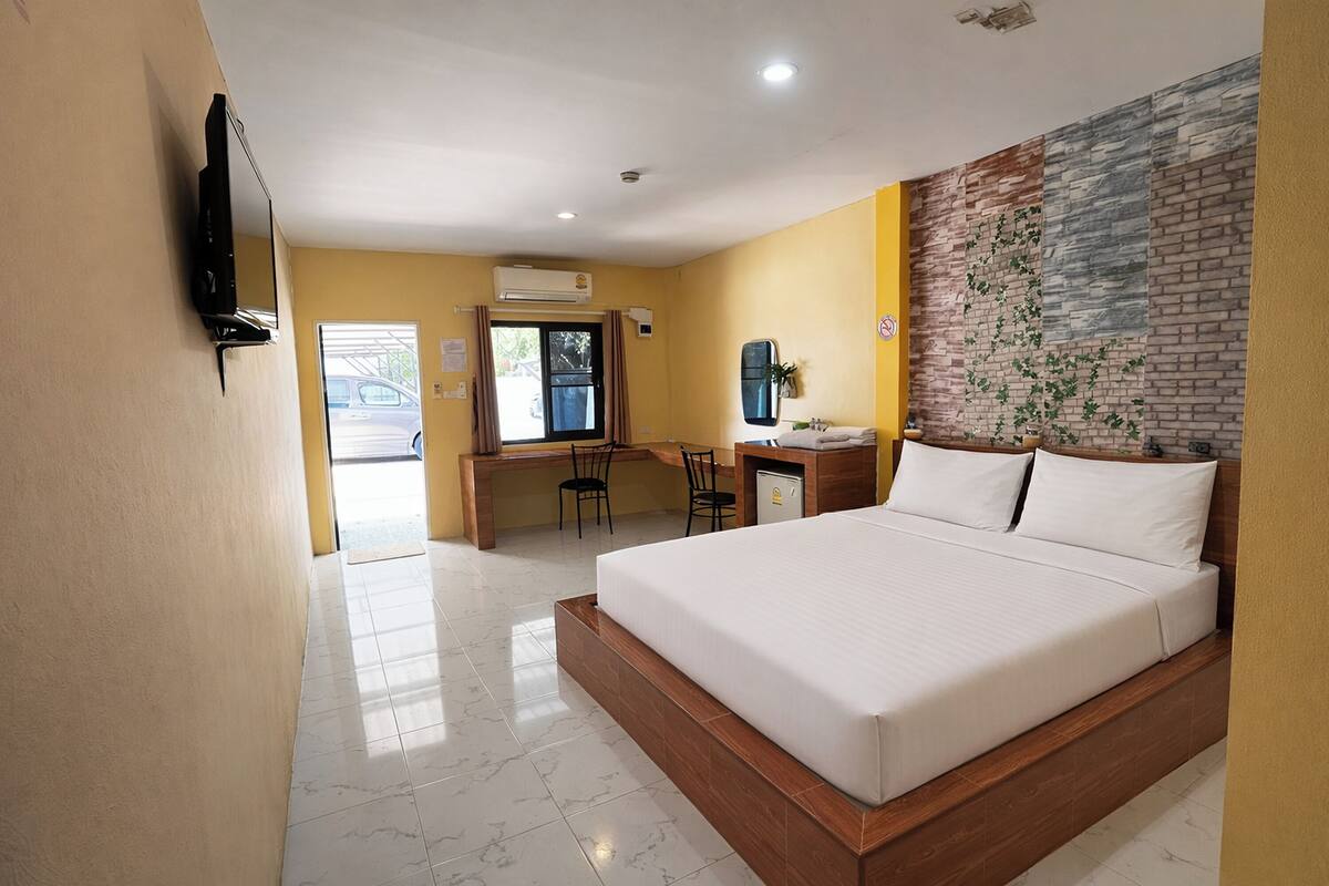 Habitación de hotel con una cama grande, un escritorio con una silla, un televisor y una ventana con cortinas.