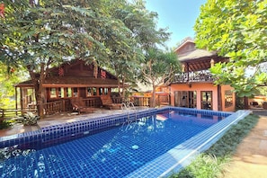 A pool area with a tiled blue pool, wooden deck, and a building with a balcony. - Baan Yung Hill Resort (Chiang Rai)