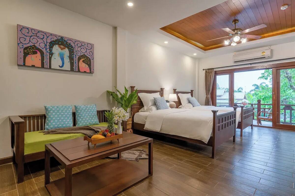 A bedroom with a bed, a sofa, a coffee table, and a painting on the wall.