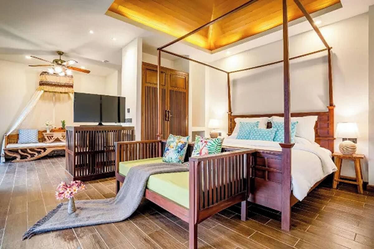 A four-poster bed with a wooden frame, a television, and a wooden wardrobe in a room with a wooden floor.