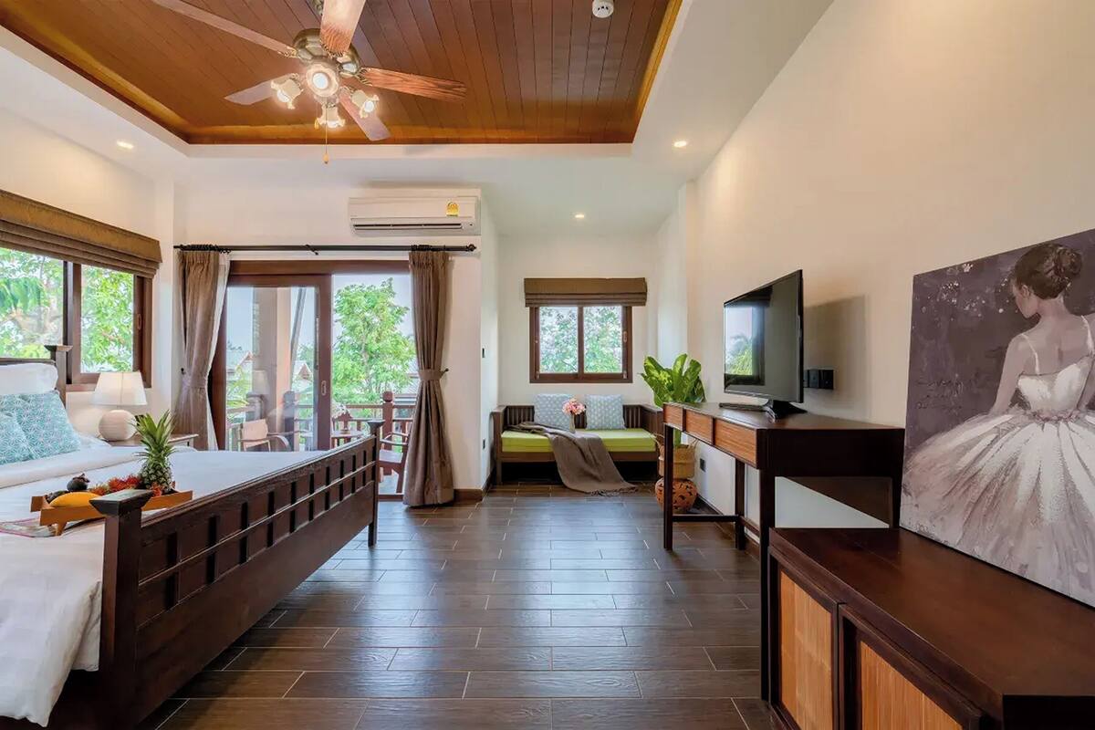 A hotel room with a bed, a sofa, a TV, and a painting.