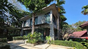 A two-story building with a balcony, surrounded by tropical vegetation and a clear sky. - Maerim Creek Resort Chiangmai (Mae Rim)