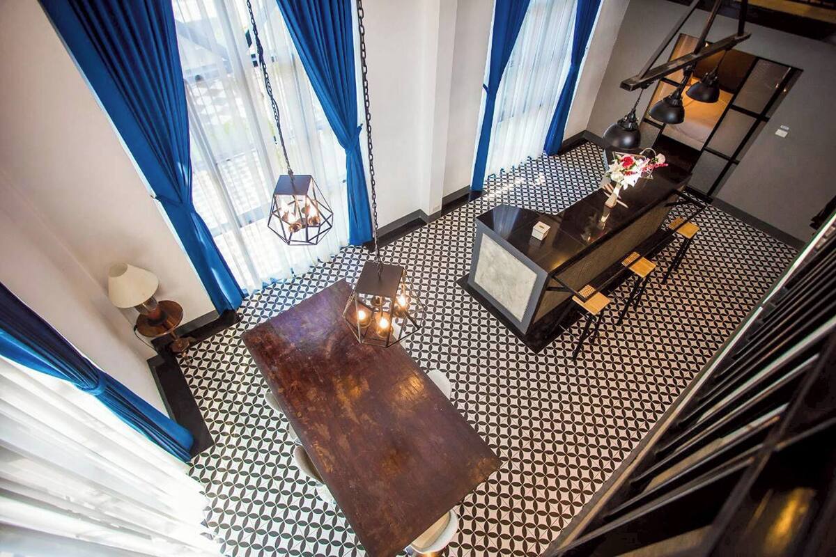 A room with a patterned floor, a central table, and a hanging light fixture.