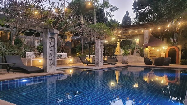 A swimming pool with lounge chairs and a small building with string lights. - Maerim Creek Resort Chiangmai (Mae Rim)