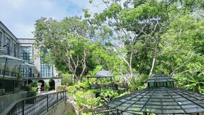 A courtyard with a gazebo, a building with large windows, and a stone wall. - Maerim Creek Resort Chiangmai (Mae Rim)