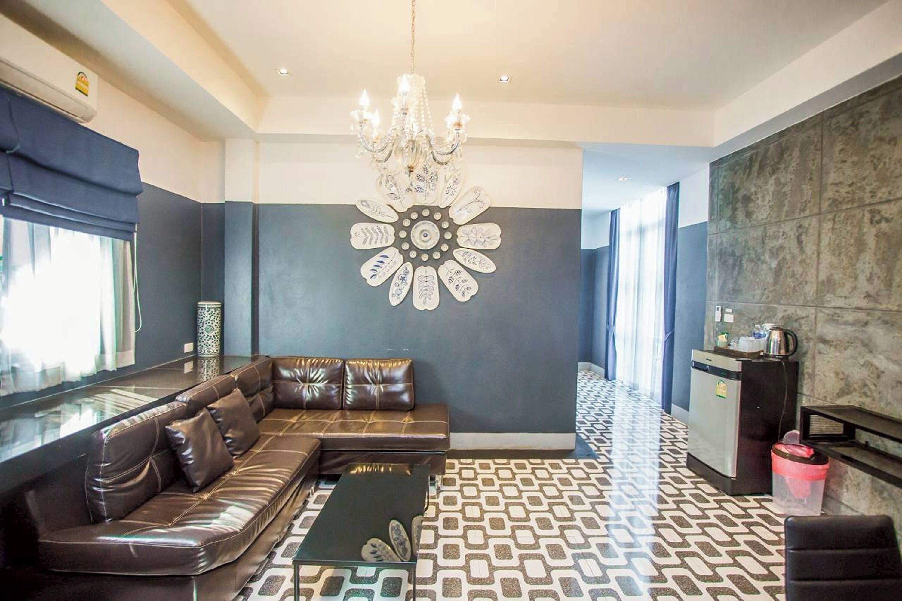 A modern living room with a leather sofa, a coffee table, a chandelier, and a decorative wall piece.