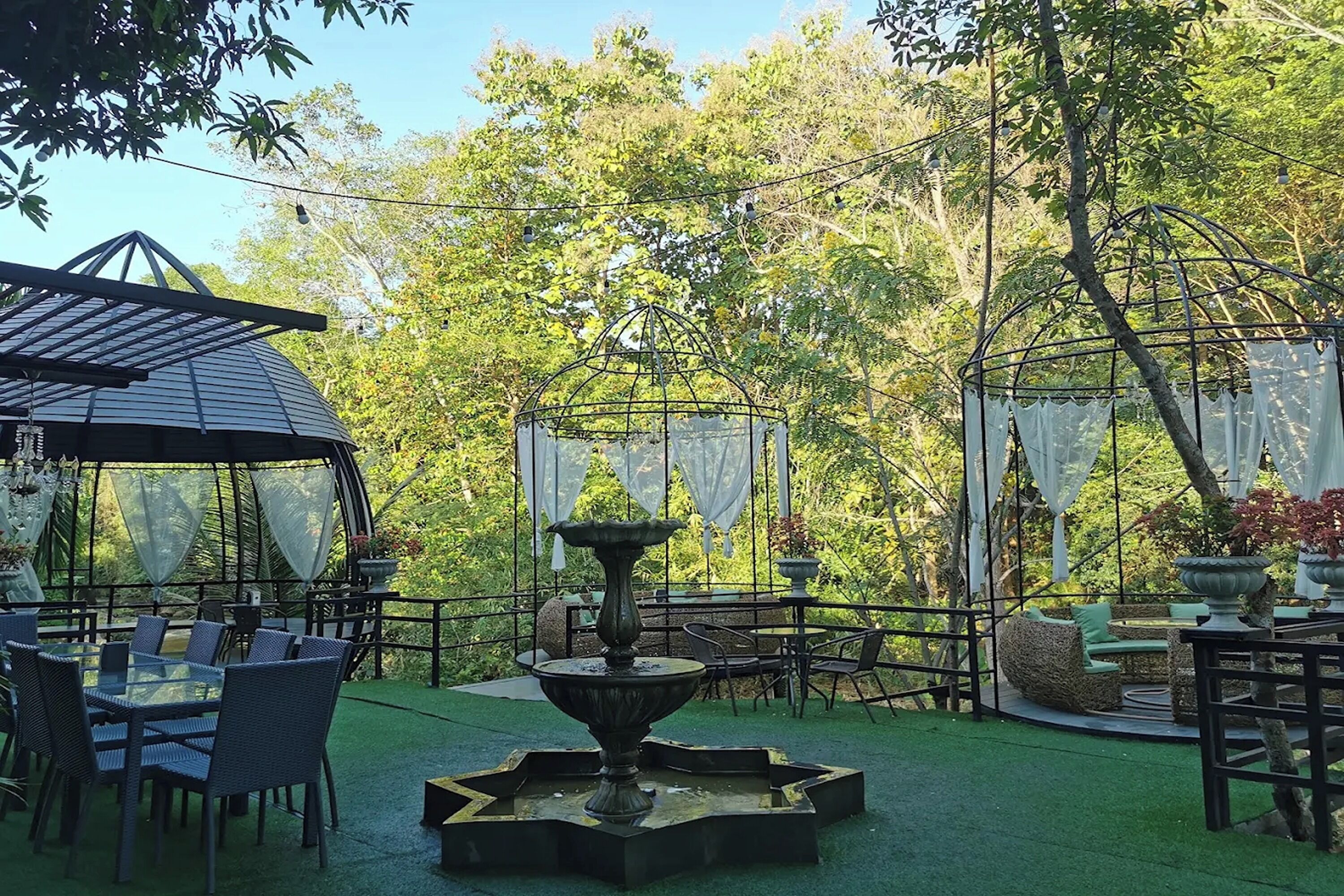 An outdoor patio area with a dining table and chairs, a decorative fountain, and a covered seating area.
