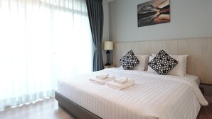 Ein Hotelzimmer mit Bett, Lampe, Gemälde und einem Fenster mit Vorhängen.