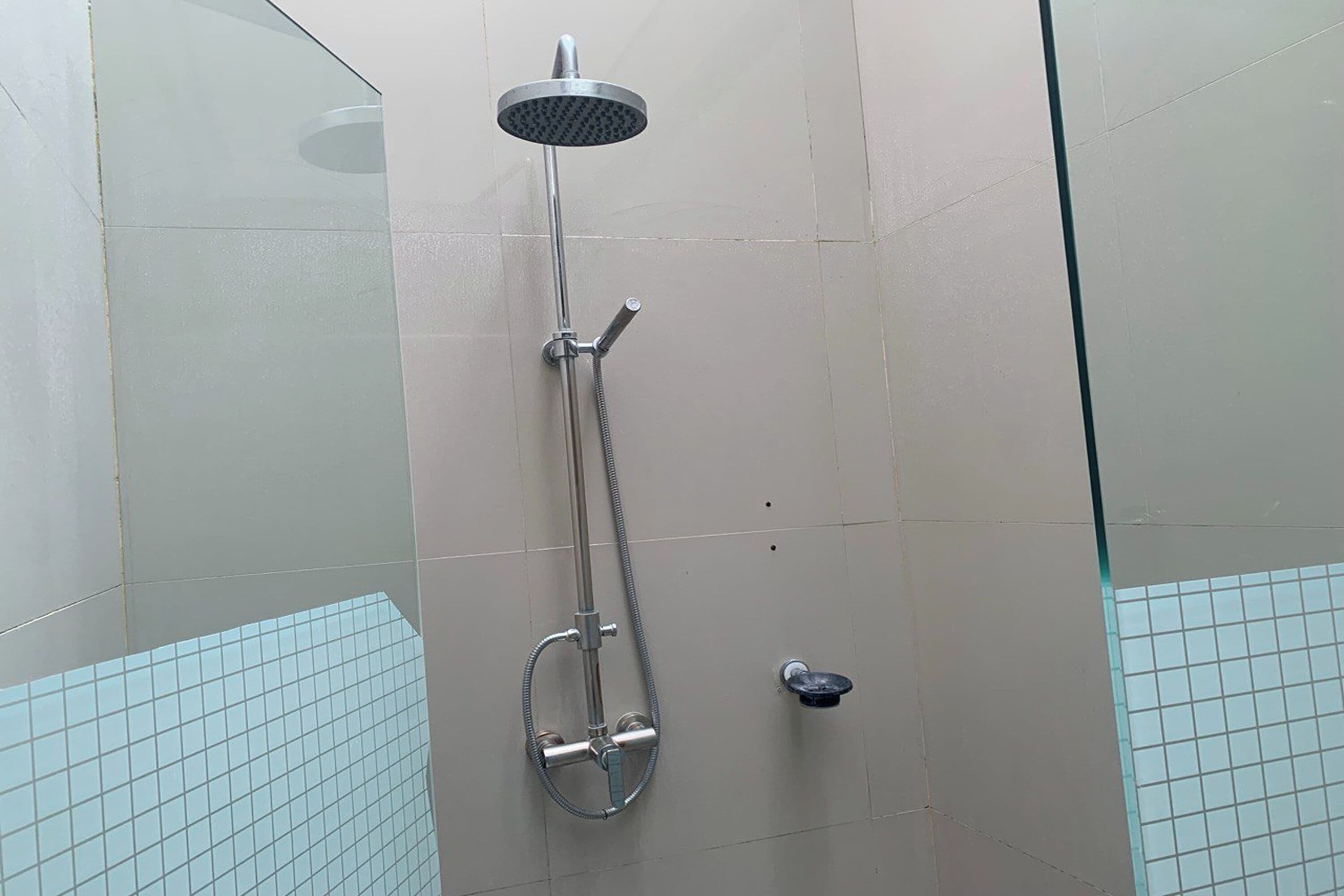 Eine Dusche mit Handbrause, Duschhandstück und verstellbarer Wandarmatur.