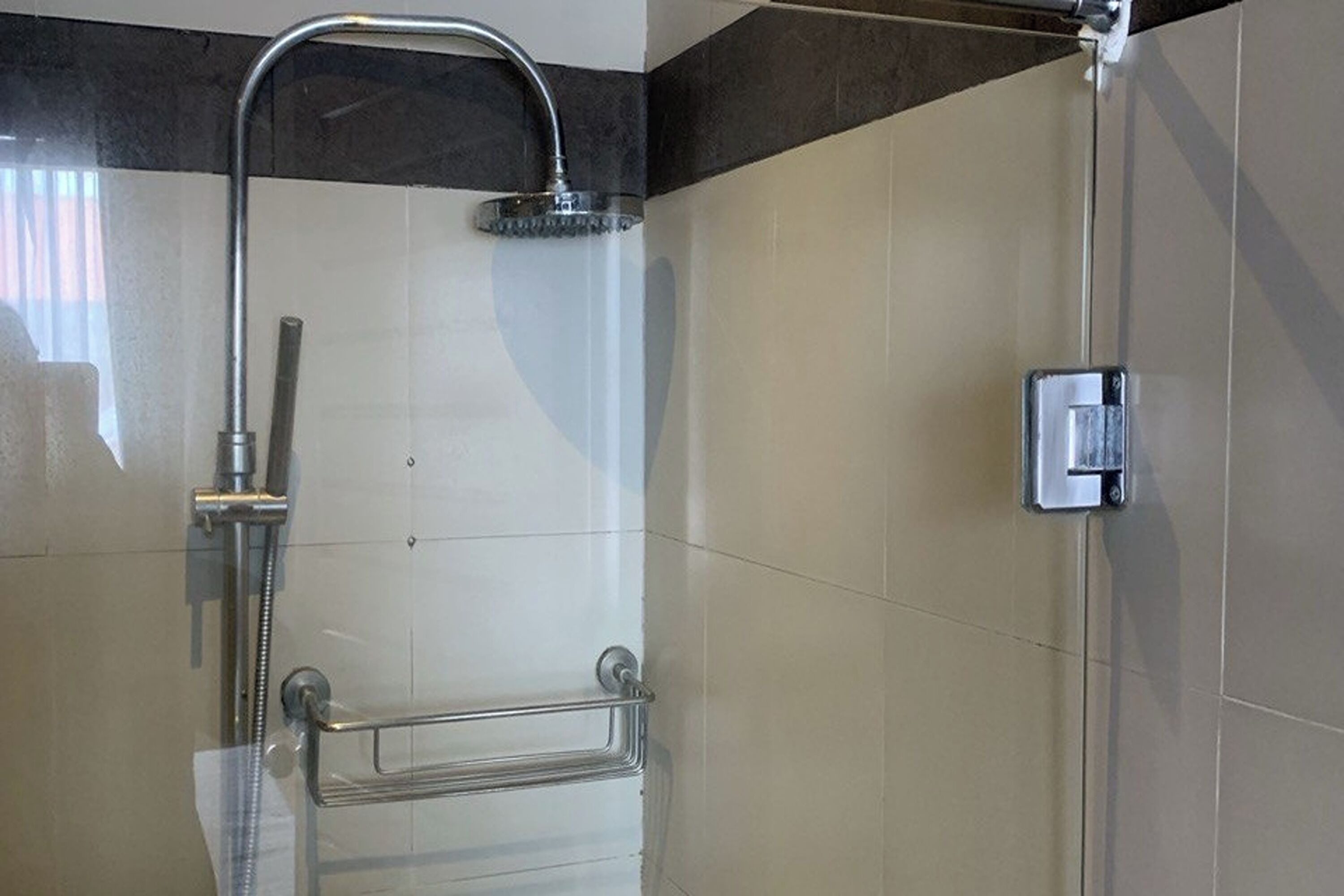 A modern bathroom with a shower, a towel rack, and a wall-mounted control panel.