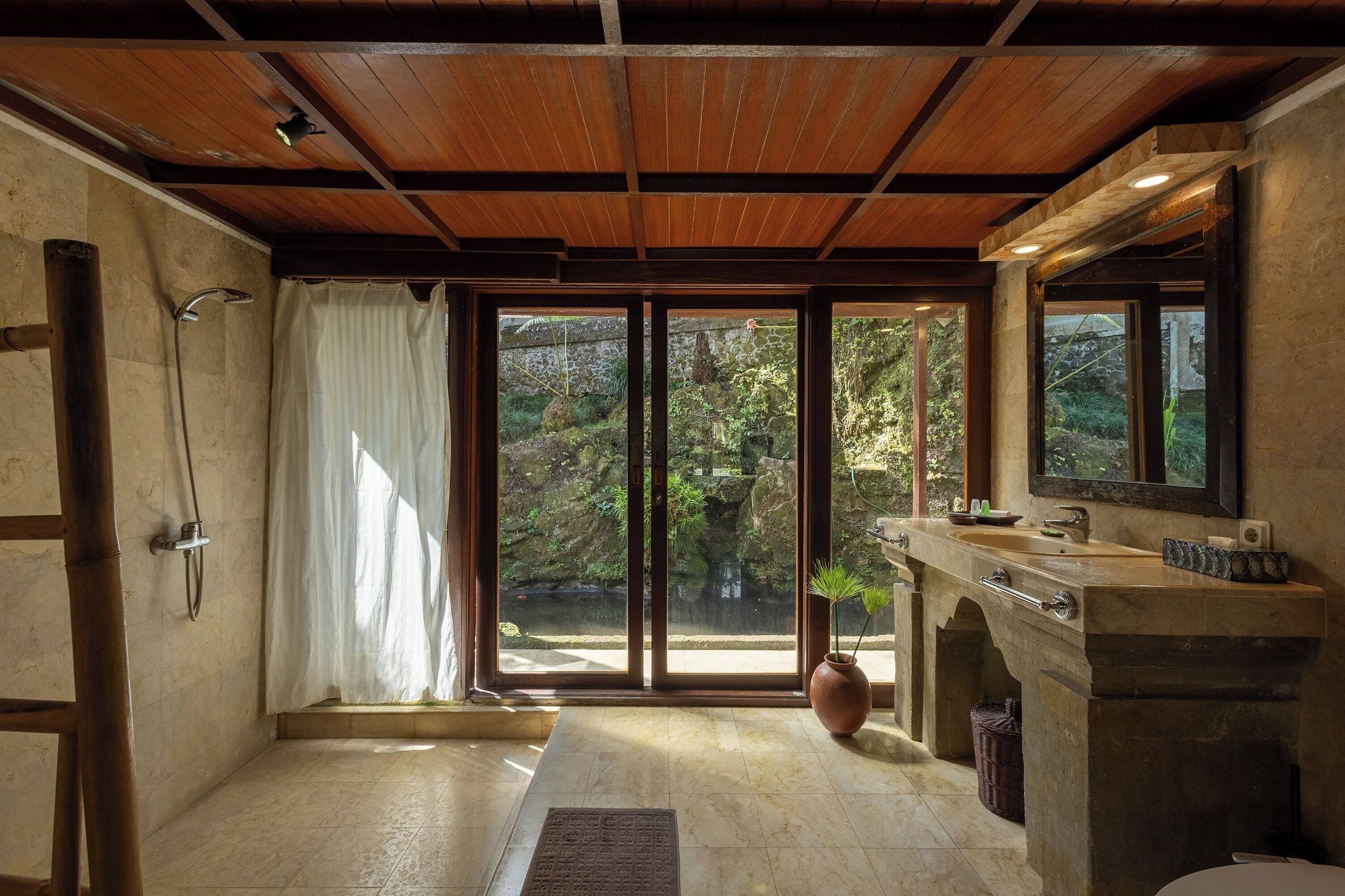 A bathroom with a shower, a sink, and a large window.