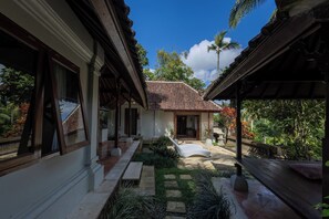 A traditional house with a tiled roof, a covered walkway, and a garden area with a bench. - Toya Retreat Villa (Gianyar)