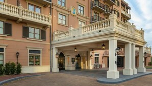 Een meerlaags hotel met een overdekte ingang, grote ramen en een balkon met leuningen.