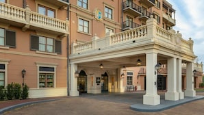Een meerlaags hotel met een overdekte ingang, grote ramen en een balkon met leuningen.