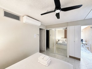 A hotel room with a bed, a ceiling fan, an air conditioning unit, a bathroom with a glass shower, and a view of the outside. - Beachside Ocean View 1BR Apartment Central Surfers (Surfers Paradise)