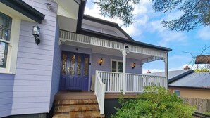 A two-story house with a purple exterior, white porch railing, and a front door with stained glass panels. - 4BR Upper House Close to Blue Mountains Highlights (Katoomba)