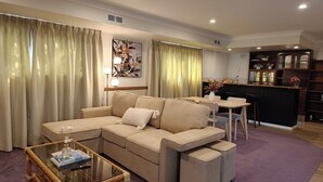 Ein Wohnzimmer mit einer Couch, einem Glastisch und einem Essbereich mit Küchenzeile.