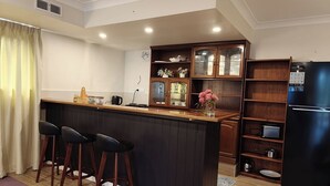 Eine moderne Küche mit Kochinsel, Barhocker, Holzschränken und einem schwarzen Kühlschrank.