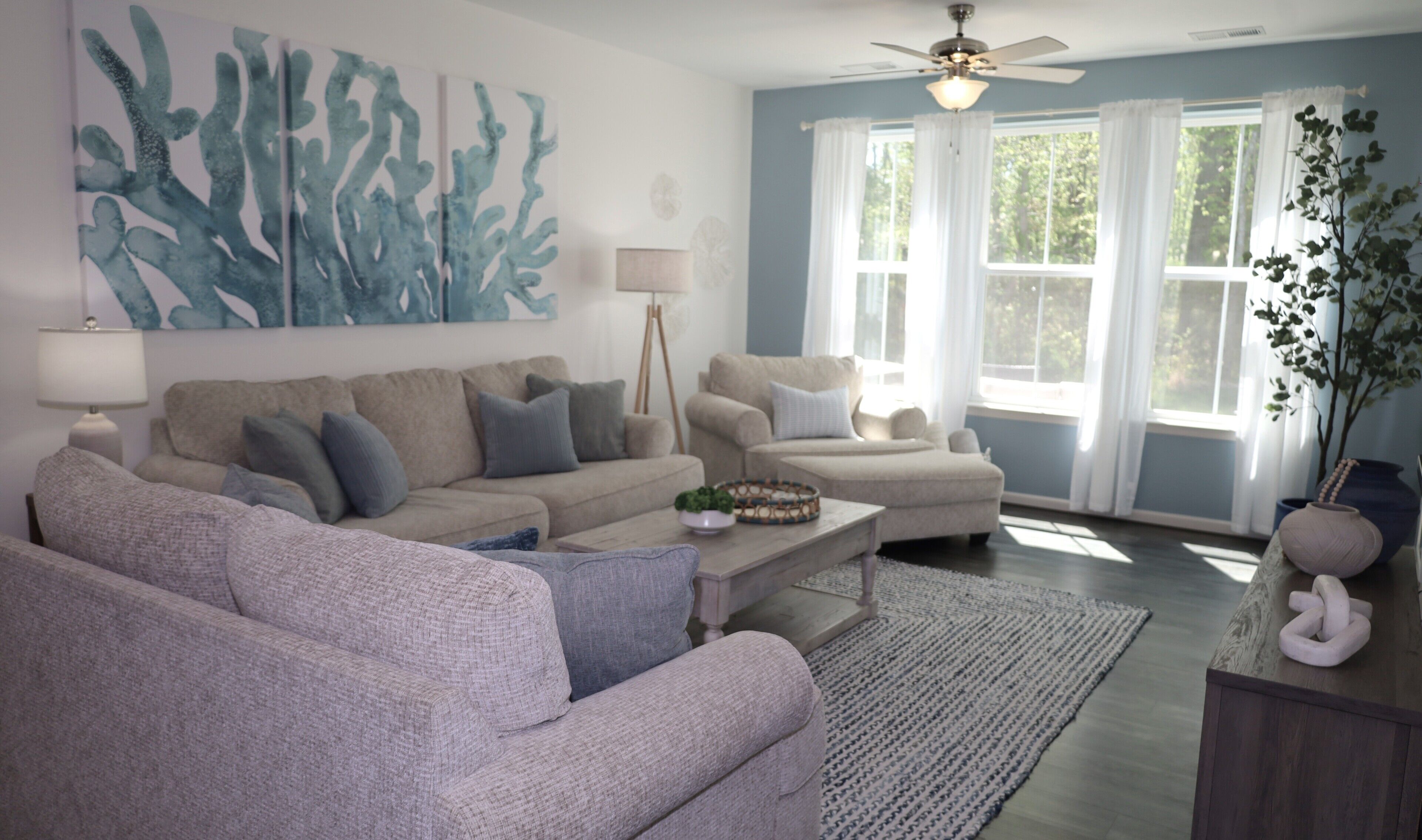 A living room with two sofas, a coffee table, a floor lamp, and a ceiling fan.