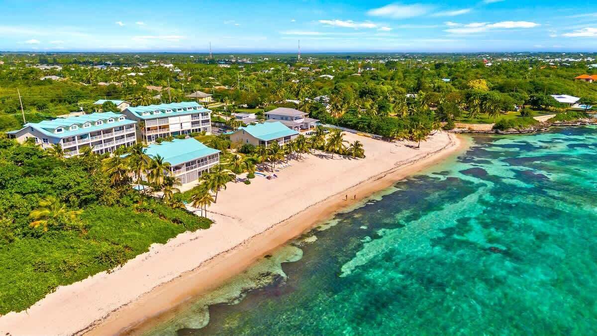 An aerial view of a resort with a beachfront, multiple buildings, and lush greenery.