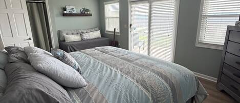 Un dormitorio con cama, ventilador de techo, cómoda y ventana con persianas.