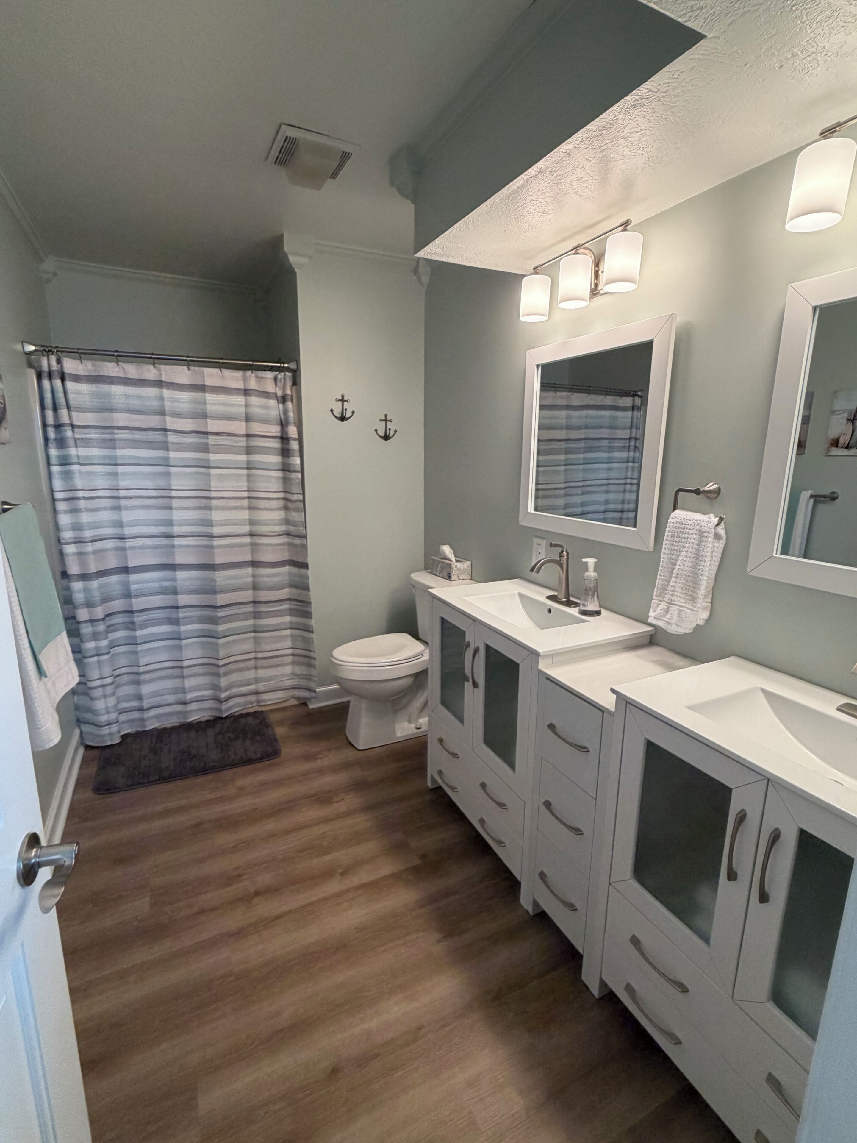 A bathroom with a toilet, a sink, a mirror, and a shower curtain.