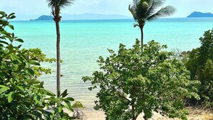 A beach with clear turquoise water, palm trees, and distant islands. - Stunning Sea View Bungalow (Tambon Ko Pha-ngan)