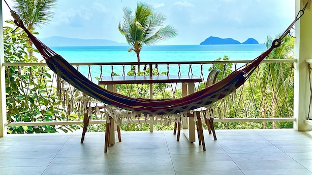A hammock chair on a balcony with a view of the ocean and palm trees. - Stunning Sea View Bungalow (Tambon Ko Pha-ngan)