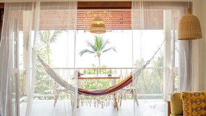 A hammock suspended between windows, a wooden table with a bowl, and a sofa with cushions. - Stunning Sea View Bungalow (Tambon Ko Pha-ngan)
