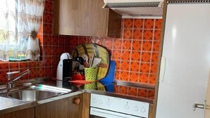 A compact kitchen with wooden cabinets, a white stove, and a red-tiled backsplash. - Haus Montanara by Interhome (Leukerbad)