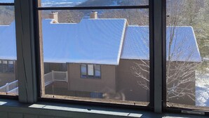 Vista a través de una ventana que muestra una casa y montañas.