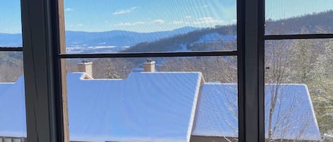A view through a window with a view of a house and mountains.