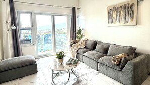 Ein modernes Wohnzimmer mit einem grauen Sofa, einem runden Couchtisch und einer Pendelleuchte.