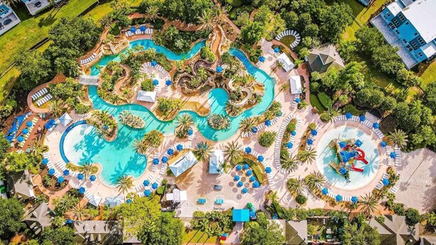 Vista aerea di un resort con diverse piscine, palme e aree relax.