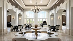 Un'ampia hall con fontana, pianoforte e zona salotto.