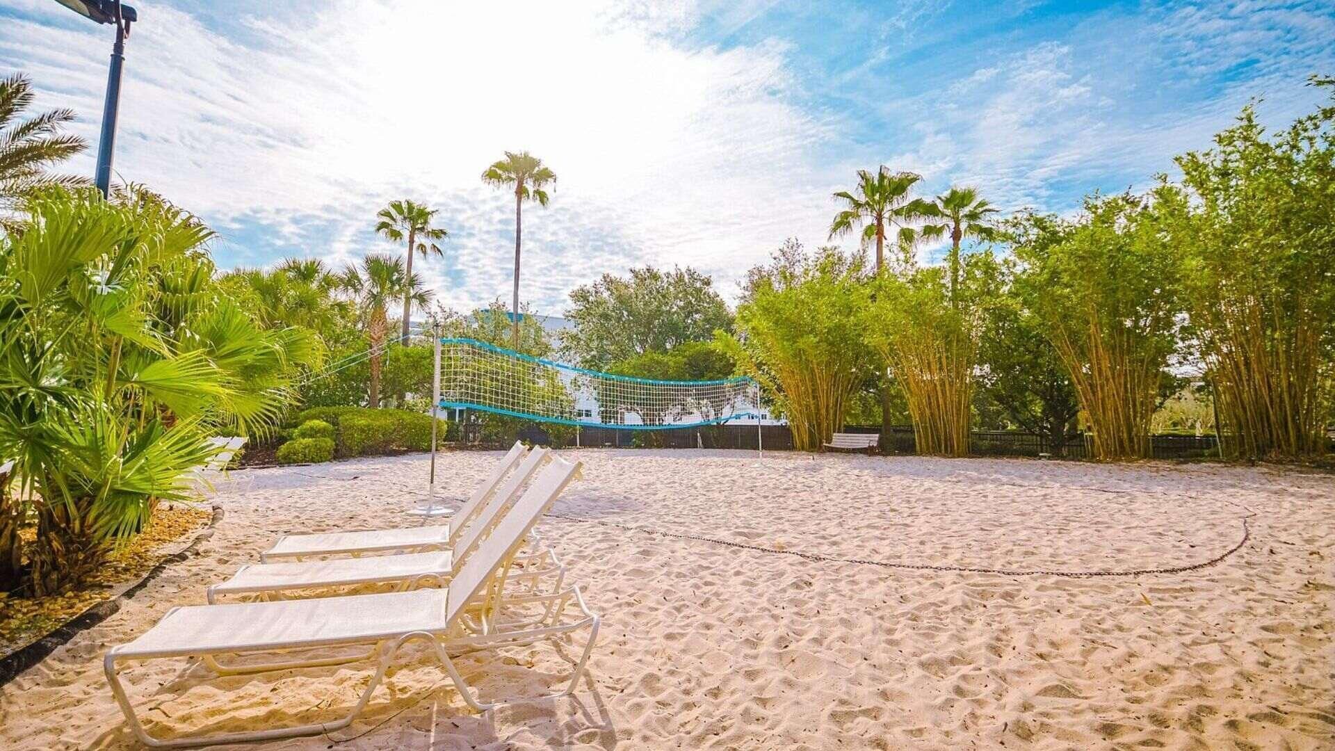 Une zone de plage sablonneuse avec un filet de volley-ball, des palmiers et un banc.