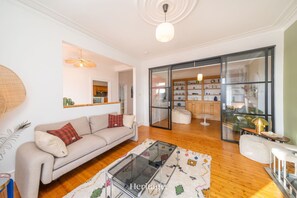 A living room with a sofa, a glass coffee table, and a large window with a view of the kitchen. - Killiegowan Self-catering Holiday Home in Aberdeen (Aberdeen)