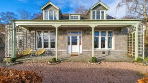 A two-story stone house with a green porch, two windows on the upper floor, and a front door. - Killiegowan Self-catering Holiday Home in Aberdeen (Aberdeen)