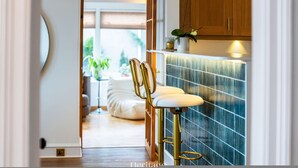 A modern kitchen with a bar stool, wooden cabinets, and a tiled backsplash. - Killiegowan Self-catering Holiday Home in Aberdeen (Aberdeen)