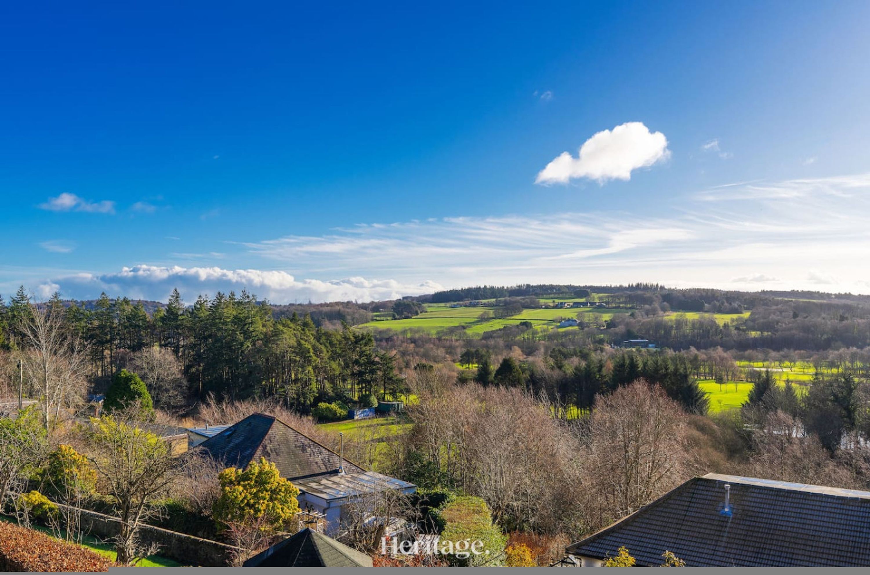 A rural landscape with a house, fields, and a clear sky.