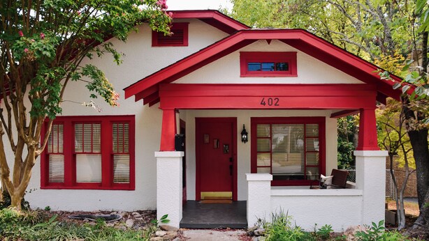 Una casa con una porta rossa e il numero 402, circondata da alberi e un sentiero in pietra.